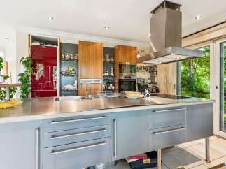 Experience modern living in this stunning kitchen featuring sleek stainless steel countertops and custom grey cabinetry.