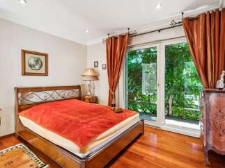 Experience serene living in this charming bedroom, featuring a comfortable bed with a vibrant orange throw and a cozy teddy bear.
