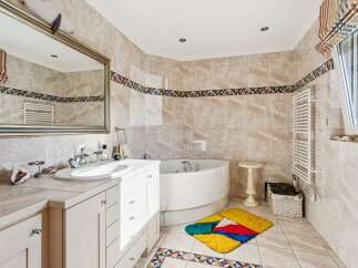 Indulge in relaxation in this luxurious bathroom featuring a spacious corner bathtub perfect for unwinding.
