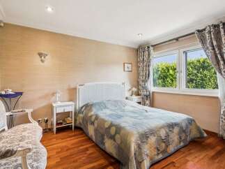 This charming bedroom features a cozy queen-size bed with a decorative white headboard, perfect for restful nights.