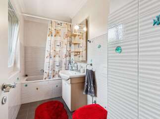 This charming bathroom features a nautical-themed shower curtain and playful fish and seashell accents, adding a touch of coastal whimsy.