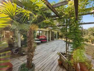 Experience seamless indoor-outdoor living with this expansive wooden deck, perfect for entertaining or relaxing amidst lush greenery.