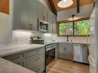 Experience the charm of this updated kitchen, featuring sleek grey cabinetry and modern stainless steel appliances.