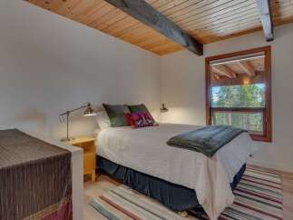 Experience cozy mountain living in this charming bedroom featuring a comfortable queen-sized bed adorned with plush pillows and a soft quilt.