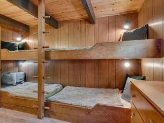 Experience cozy cabin living with these charming wooden bunk beds, perfect for maximizing space in a rustic retreat.
