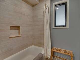 This modern bathroom features a sleek bathtub with a built-in niche for convenient storage.