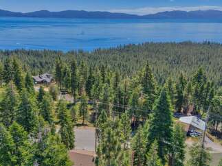 Nestled amidst a dense forest of pine trees, this property offers breathtaking panoramic views of a vast, blue lake and distant mountains.
