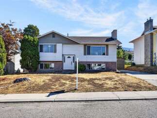 Charming split-level home featuring a classic white exterior with brick accents and a prominent chimney.