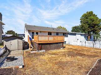 Enjoy outdoor living with this spacious backyard featuring a large wooden deck perfect for entertaining.