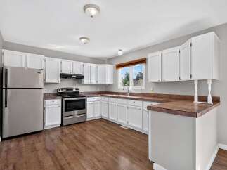 Discover this charming kitchen featuring crisp white cabinetry and a sleek stainless steel refrigerator.