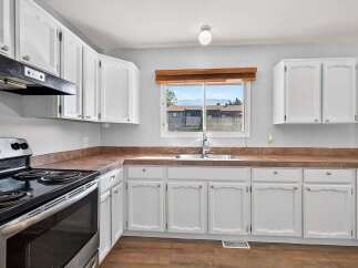 This charming kitchen features crisp white cabinetry offering ample storage, complemented by a warm, earthy-toned countertop.