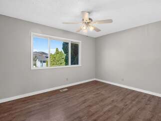 This spacious room features a large window offering scenic views of the surrounding landscape and lush green trees.