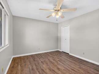 This spacious room features a modern ceiling fan and beautiful wood-look flooring, creating a warm and inviting atmosphere.