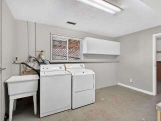 This laundry room offers ample space and functionality with a large utility sink and a stacked washer and dryer.