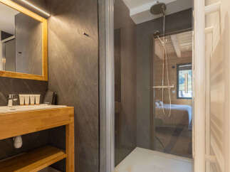 Experience modern comfort in this well-appointed bathroom, featuring a sleek vanity with a wooden countertop and a spacious walk-in shower with a rainfall showerhead.