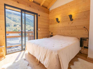 Experience breathtaking mountain views from this charming wooden bedroom, featuring a comfortable bed and a large sliding glass door that opens to a private balcony.