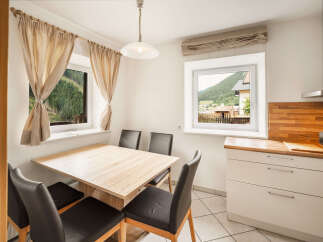Enjoy meals with a view in this charming dining area, featuring a light wood table and comfortable black chairs.
