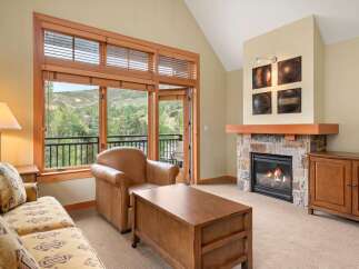 Experience cozy living in this inviting living room featuring a stone fireplace and a comfortable leather armchair.