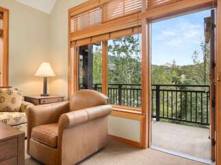 Experience breathtaking mountain views from this inviting living space, featuring a comfortable leather armchair and a patterned sofa.
