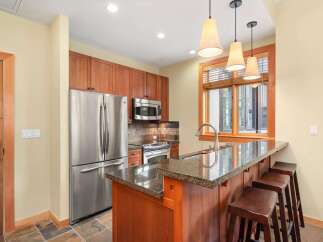 This charming kitchen features sleek stainless steel appliances, including a refrigerator and microwave, complemented by warm cherry wood cabinetry.