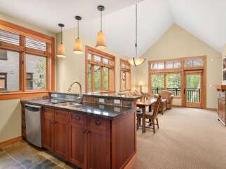 This charming living space features a well-appointed kitchen with rich wood cabinetry and granite countertops, seamlessly flowing into a dining area and living room.