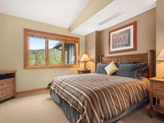 Experience comfort and style in this inviting bedroom, featuring a plush king-sized bed adorned with a striped comforter and dark gray pillows.