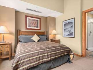 Experience comfort and style in this inviting bedroom, featuring a plush king-sized bed adorned with a striped comforter and coordinating pillows.