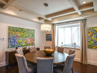 Experience elegant dining in this beautifully appointed room, featuring a large round wooden table surrounded by plush upholstered chairs.