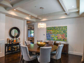 This elegant dining room features a round wooden table surrounded by plush upholstered chairs, perfect for intimate gatherings.