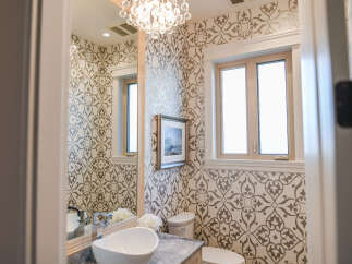 This powder room features elegant damask wallpaper and a striking crystal chandelier.