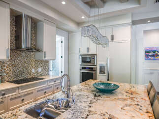 Experience luxury in this stunning kitchen, featuring a sleek stainless steel range hood, a beautiful mosaic tile backsplash, and a spacious granite island perfect for entertaining.