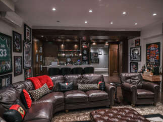 Experience ultimate relaxation in this luxurious home entertainment space, featuring a fully equipped bar and plush leather seating.