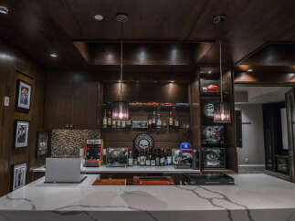 Step into this sophisticated home bar, featuring rich wood paneling and a stunning marble countertop.