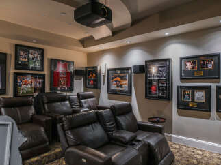 Experience ultimate entertainment in this dedicated home theater, featuring plush leather recliners and a projector for an immersive cinematic experience.