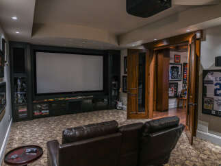 Experience ultimate entertainment in this luxurious home theater, featuring a massive projector screen and plush leather seating perfect for movie nights.