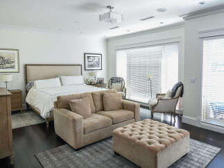 Experience luxury in this spacious master suite, featuring a king-sized bed with crisp white linens and a plush upholstered headboard.