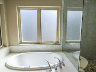Indulge in luxury with this stunning bathroom featuring a spacious soaking tub and a separate glass-enclosed shower.