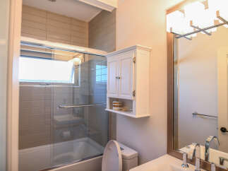 This modern bathroom features a sleek bathtub with a glass enclosure and a convenient shower handle.