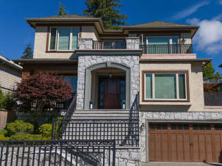 This stunning two-story home boasts a charming stone facade and an inviting arched entryway, leading to a beautifully crafted wooden door.