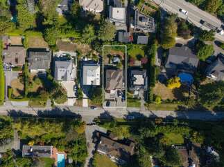 Discover this stunning aerial view of a modern residence featuring a spacious backyard with lush greenery and mature trees.