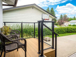 Enjoy outdoor living on this charming deck featuring comfortable wicker chairs and a modern glass railing.