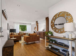 Step into a welcoming living space featuring comfortable brown sofas and a stylish console table adorned with a unique hexagonal mirror.