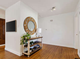 Step into this inviting entryway featuring a sleek wall-mounted television and a decorative hexagonal mirror.