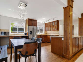 This spacious kitchen and dining area features rich wood cabinetry and gleaming stainless steel appliances.