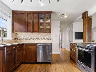 This kitchen boasts beautiful dark wood cabinetry complemented by a stylish tile backsplash and granite countertops.