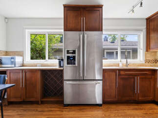 This spacious kitchen features a large stainless steel refrigerator with a built-in water and ice dispenser, complemented by rich wooden cabinetry.