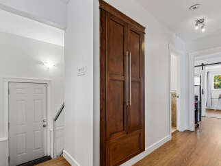 This hallway features a tall, dark wood cabinet with silver handles, offering ample storage.