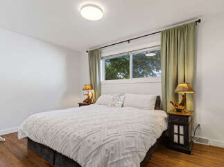 This inviting bedroom features a plush white tufted comforter on a queen-sized bed, complemented by two matching pillows and a decorative accent pillow.