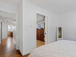 Step into this inviting bedroom featuring a plush white comforter and a full-length mirror, perfect for getting ready.