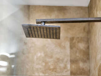 Experience modern luxury in this bathroom, featuring a sleek, square rainfall showerhead for an invigorating shower experience.